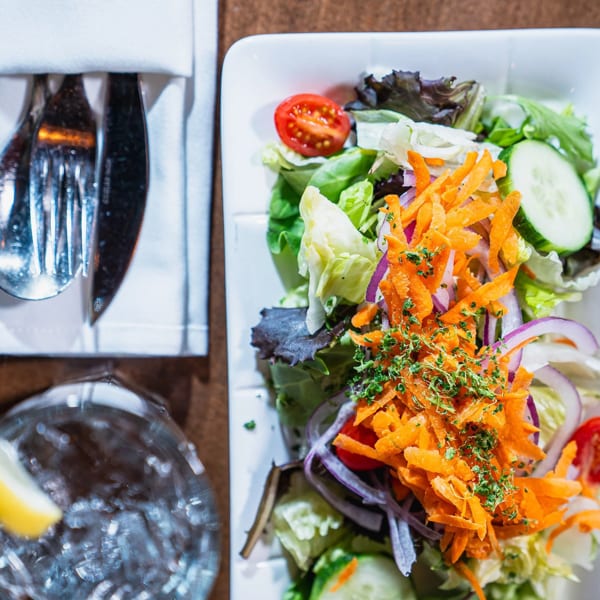 Overhead view of a fresh garden salad with shredded carrots, red onion, and cherry tomatoes.