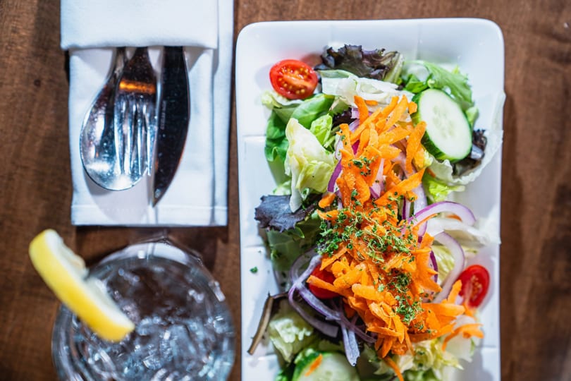 Overhead view of a fresh garden salad with shredded carrots, red onion, and cherry tomatoes.