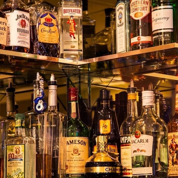 A well-stocked bar shelf with various liquor bottles, including whiskey, rum, gin, and vodka.